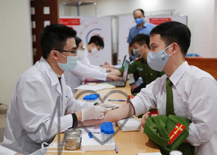 Doctor collecting blood sample from a young man during a medical blood test camp.