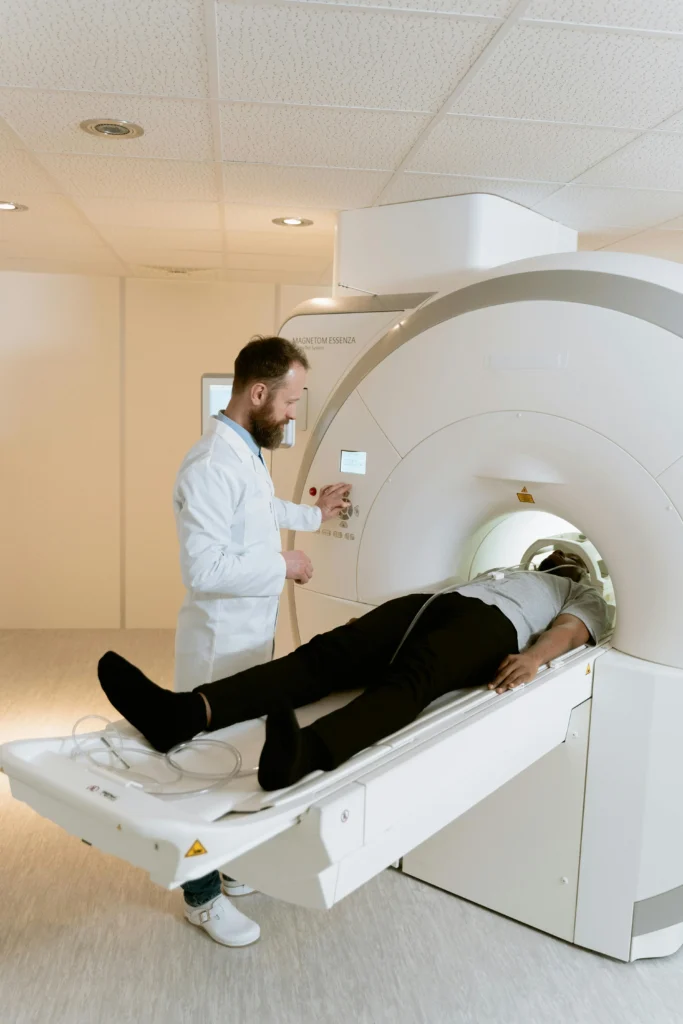 Patient undergoing MRI scan with technician assistance in radiology room