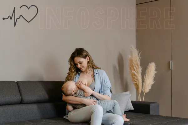 Mother breastfeeding her baby on a couch in a cozy living room.