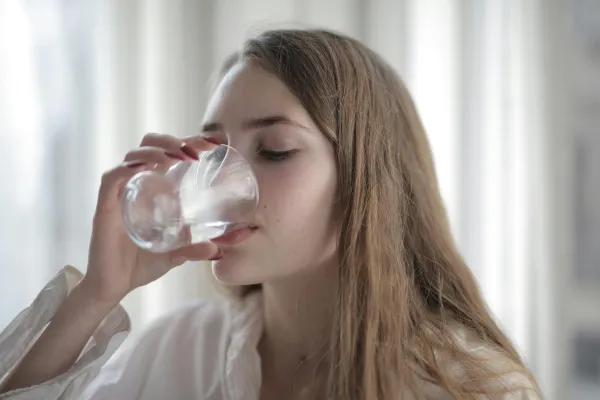 Woman drinking water to stay hydrated during menstrual cycle